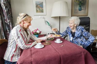 Dame heeft alarmknop om haar hals en drinkt koffie met haar dochter