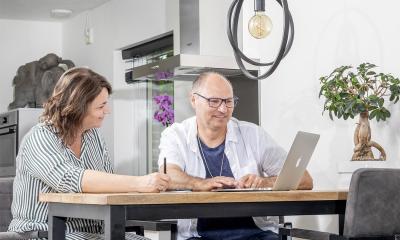 vrouw helpt man om online personenalarmering aan te vragen